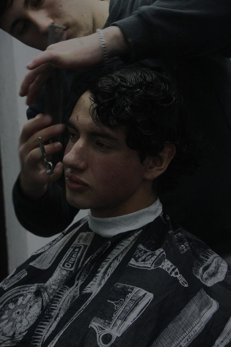 A man getting his hair cut at a barber shop